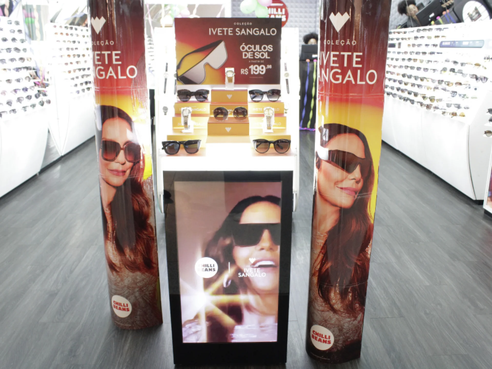 Display de óculos de sol da "Coleção Ivete Sangalo" da Chilli Beans, flanqueado por grandes banners da artista.