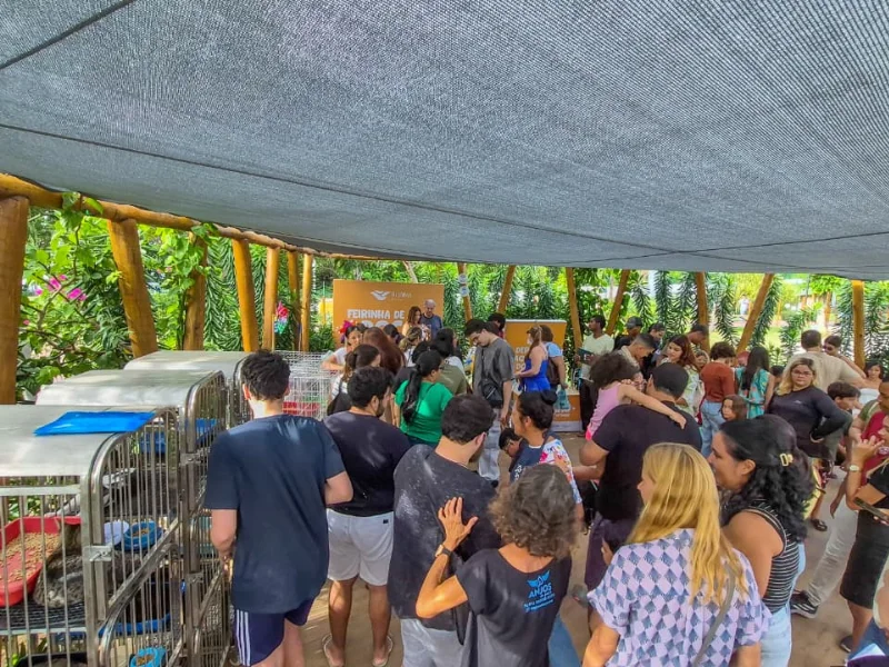 Vista geral do evento com muitas pessoas circulando em uma área coberta com tendas e cercados para animais.