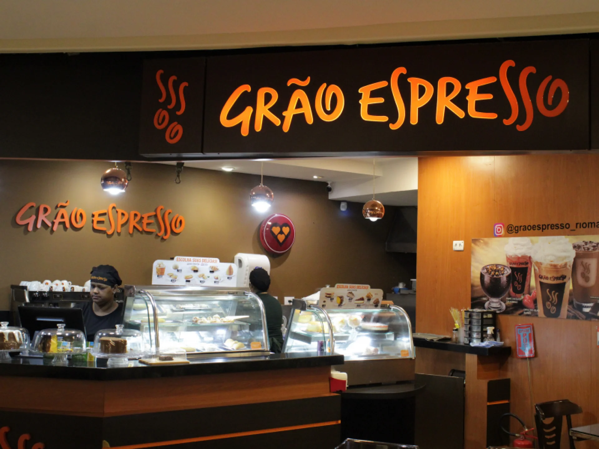 A imagem mostra a fachada da cafeteria "Grão Espresso", com seu letreiro em laranja.