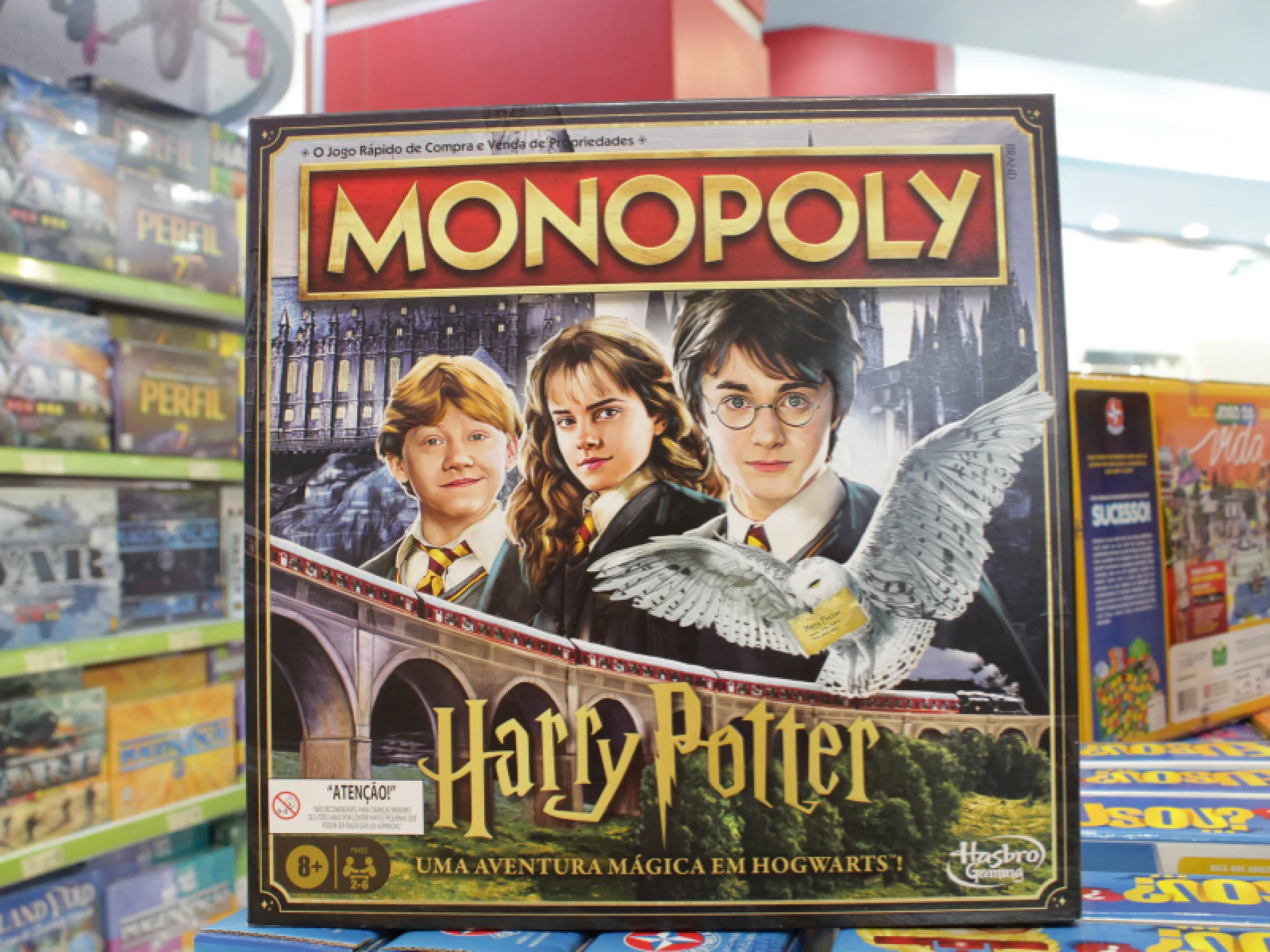 A imagem mostra a caixa do jogo de tabuleiro Monopoly com o tema "Harry Potter", apresentando os personagens principais. A imagem mostra a caixa do jogo de tabuleiro Monopoly com o tema "Harry Potter", apresentando os personagens principais.