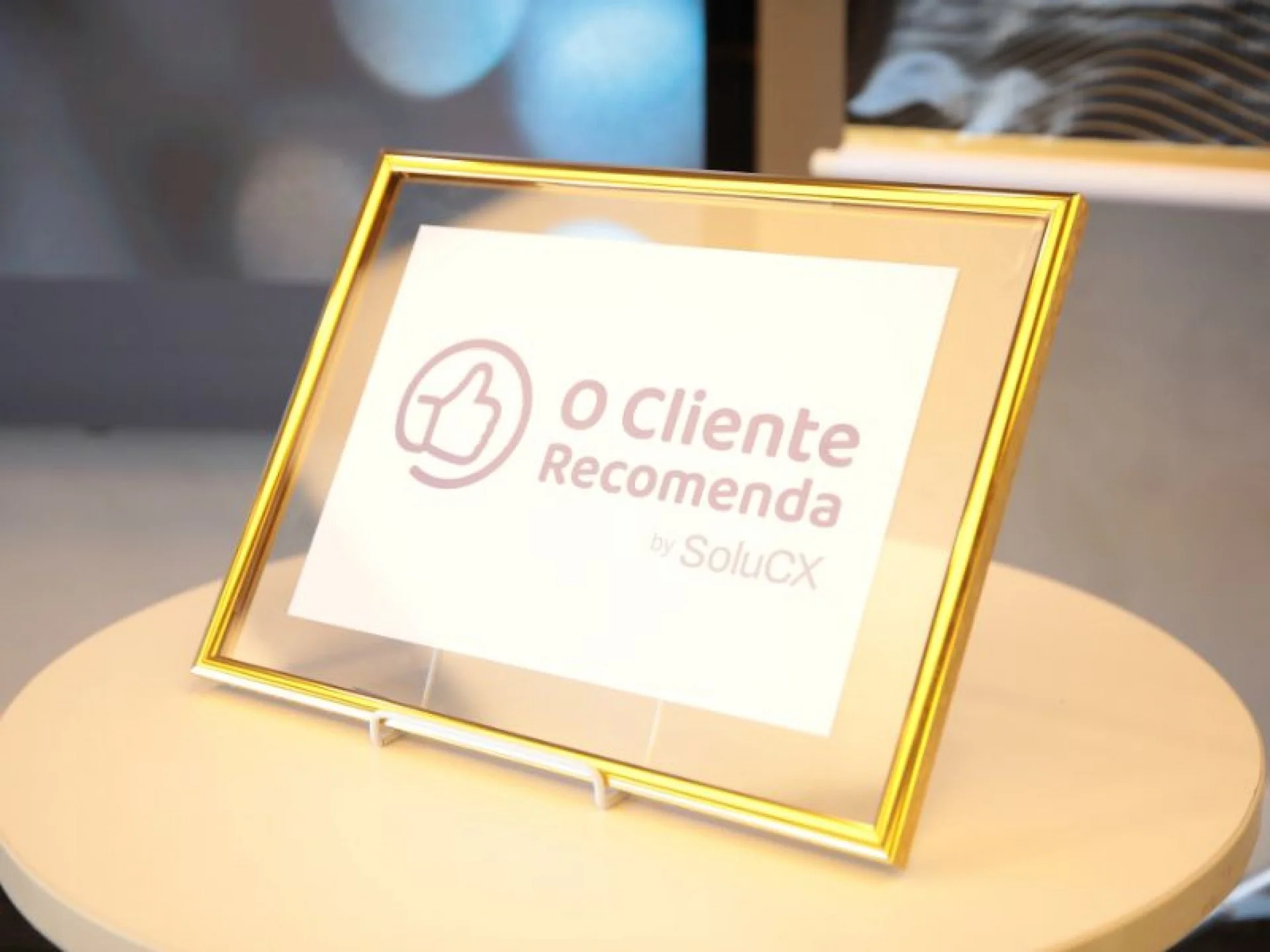 Imagem de uma placa com o a frase "O Cliente Recomenda by SoluCX" em moldura dourada.