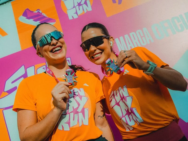 Duas mulheres jovens sorriem alegremente para a foto após uma corrida.