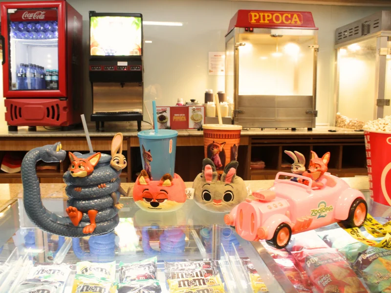 Vista geral dos quatro colecionáveis temáticos de Zootopia do Cinemark: o Copo Cobra, o Balde Carro e os dois modelos de bolsa de pelúcia porta-copo.